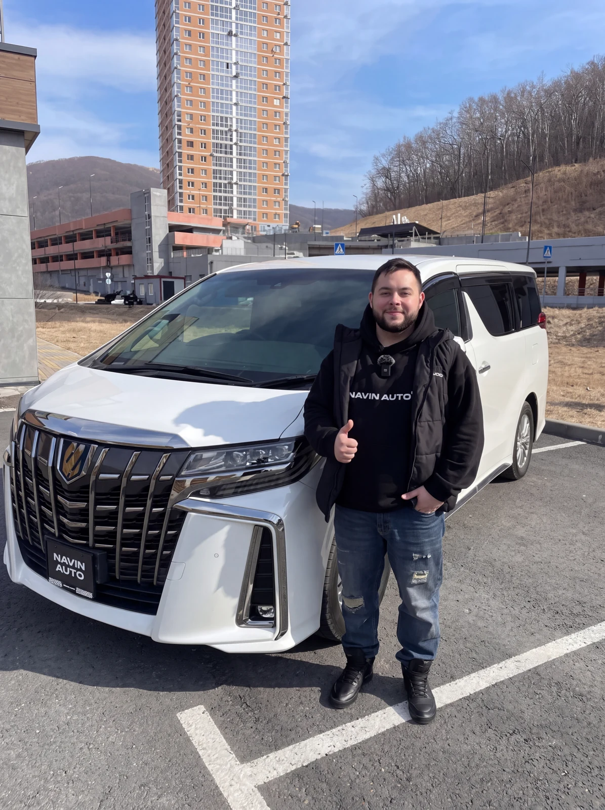 Макс Навин рядом с автомобилем NAVIN AUTO. Исходная фотография компании, улучшенная с помощью ИИ